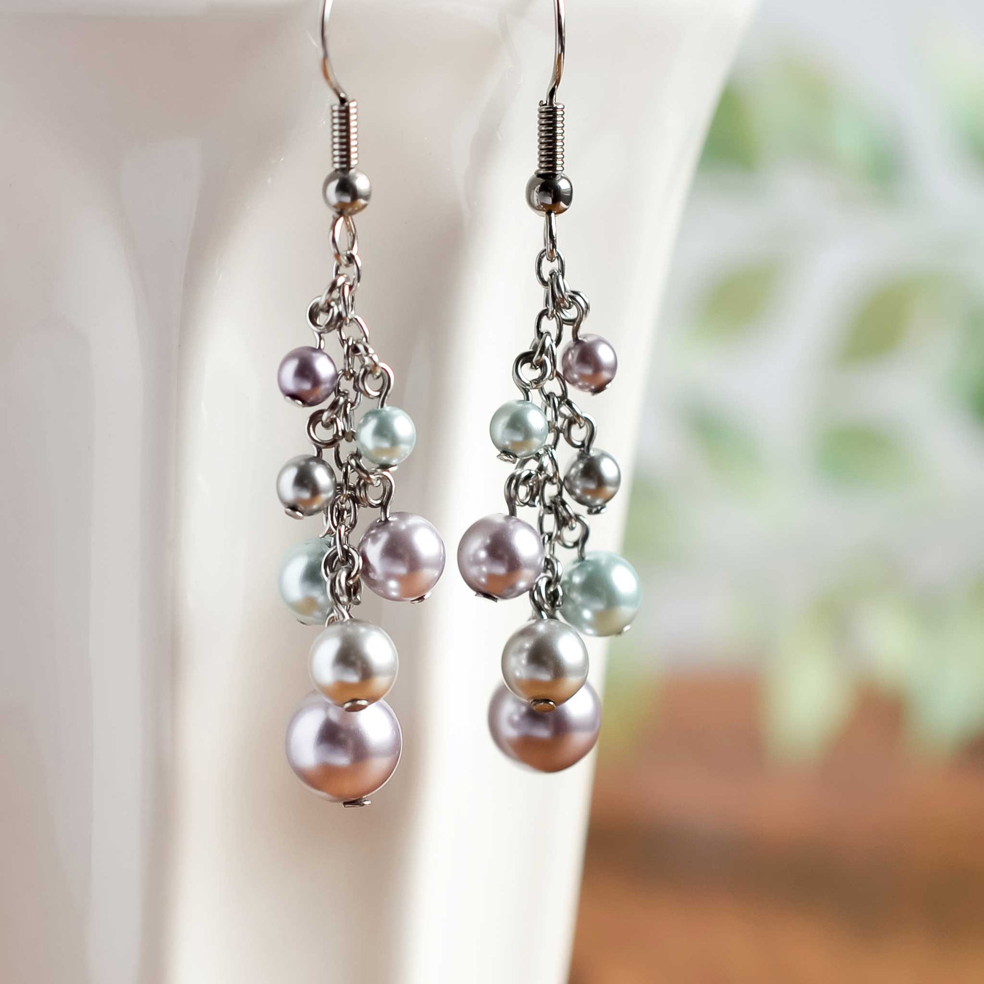 Faux pearl cluster drop earrings hanging from white cup