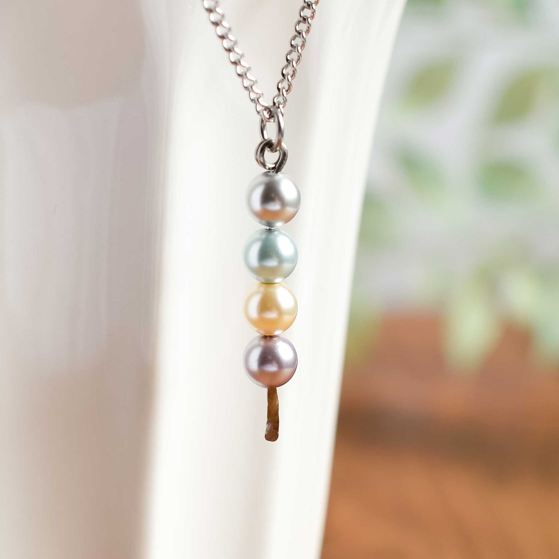 Faux pastel pearl stack pendant hanging on white cup