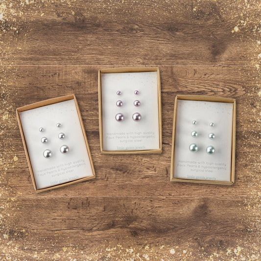 Faux pearl stud earring gift sets on dark wood background