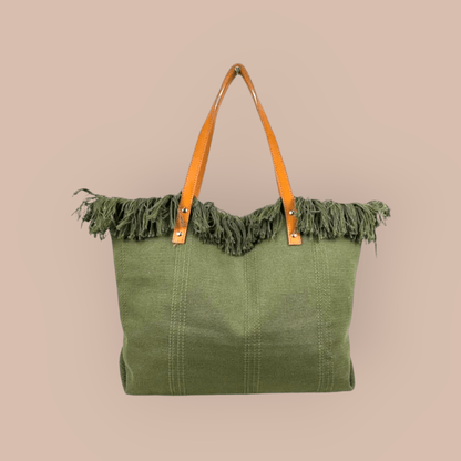 Green tote bag with frayed edge and brown leather handles on a beige background