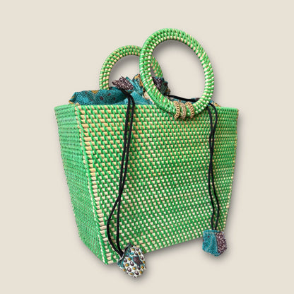 Green woven handbag with decorative handles and strap on a beige background