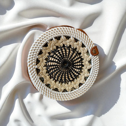 Round woven bag with a spiral pattern on a white fabric background