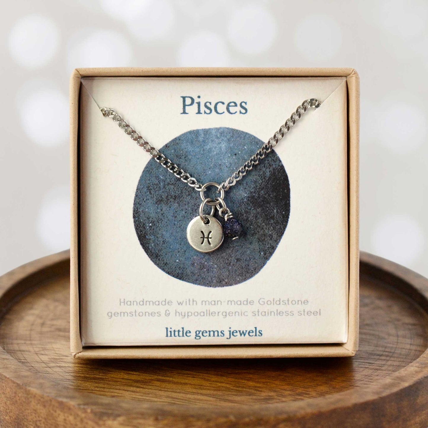 Dainty Pisces zodiac sign necklace in eco-friendly gift box on wooden coaster