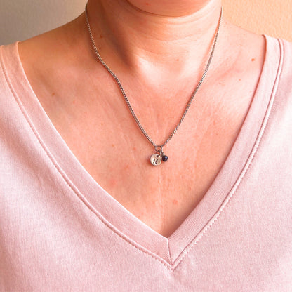 Woman wearing a pink v neck top and dainty Pisces zodiac sign necklace.