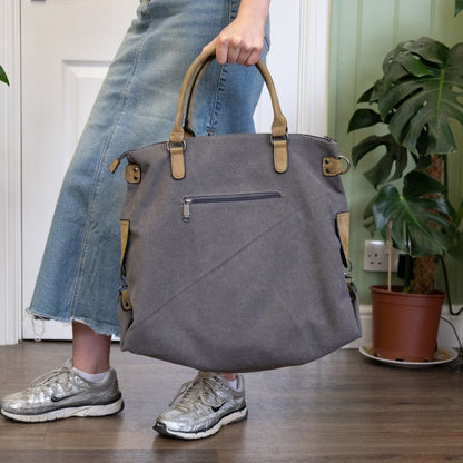 Person holding a gray handbag indoors with a plant in the background