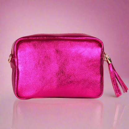 Pink metallic handbag with gold accents on a pink background