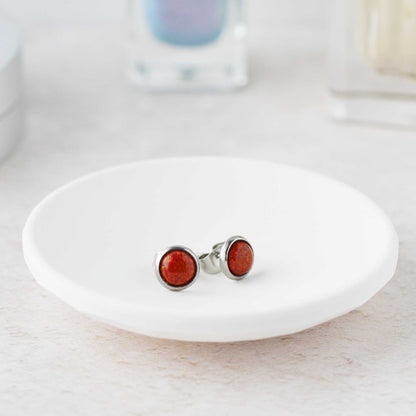 Silver earrings with red stones on a white dish