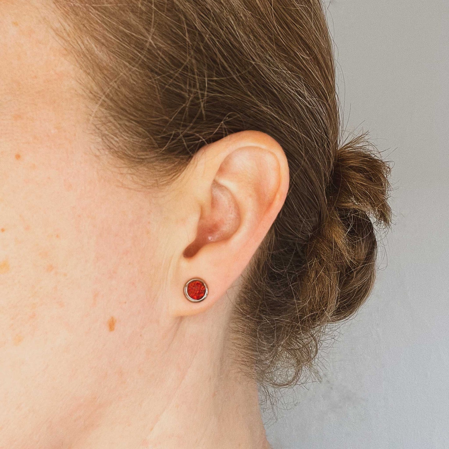 Woman wearing red Opal stud earring in earlobe