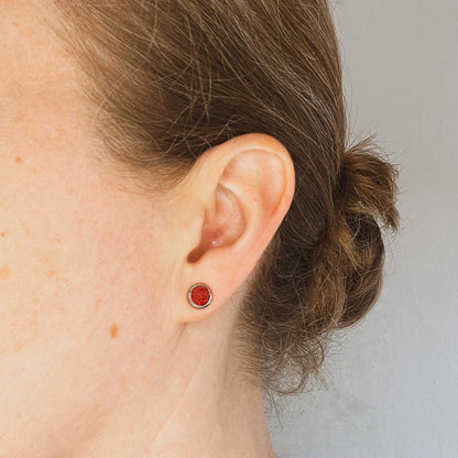Woman wearing red Opal stud earring in earlobe