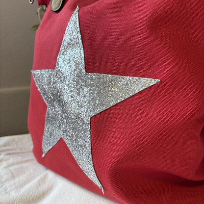 Red bag with a silver glittery star on a neutral background