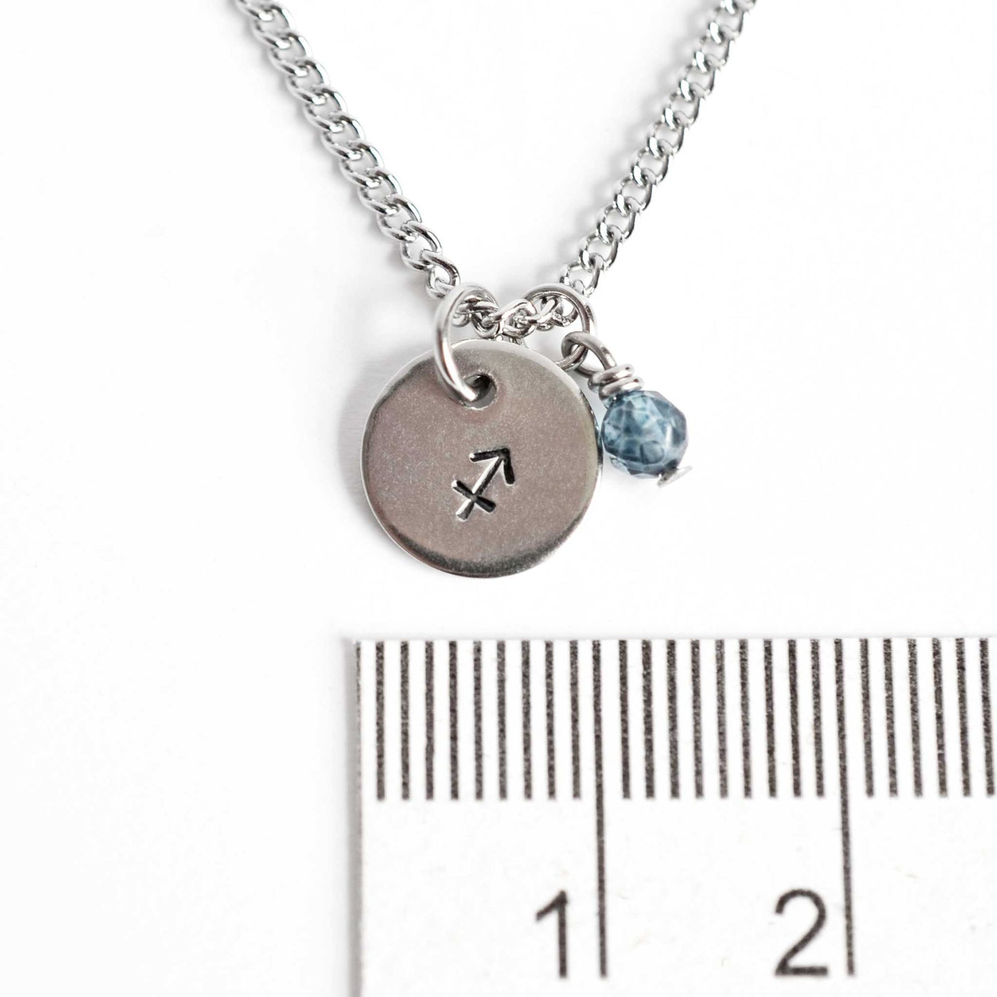 1cm diameter disc pendant with hand stamped Sagittarius zodiac sign and 4mm Topaz gemstone charm