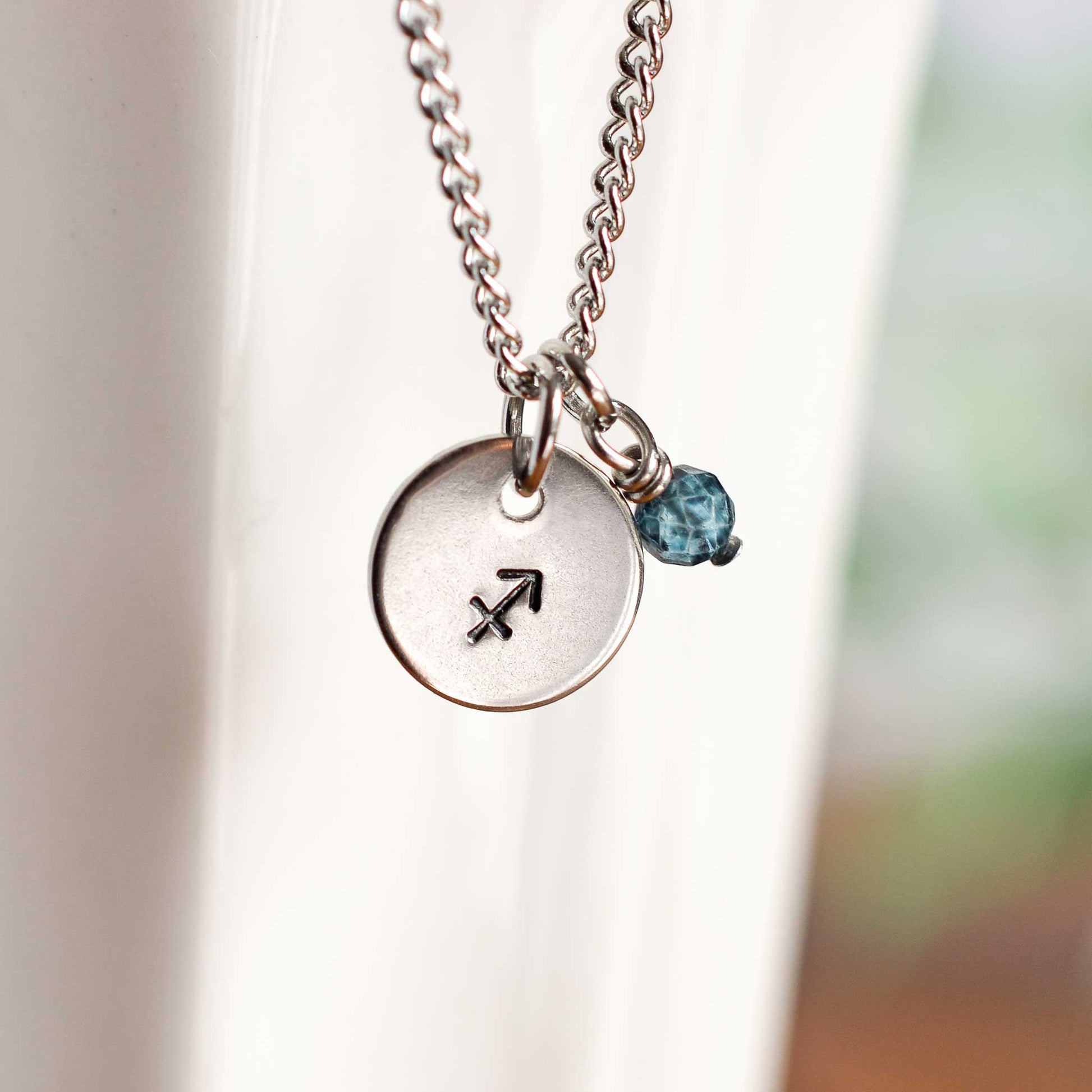 Close up of Sagittarius zodiac sign necklace with Topaz gemstone charm on stainless steel chain