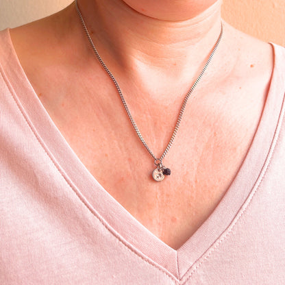 Woman wearing a pink v neck top and dainty Sagittarius zodiac sign necklace.