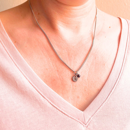 Woman wearing a pink v neck top and dainty Scorpio zodiac sign necklace.