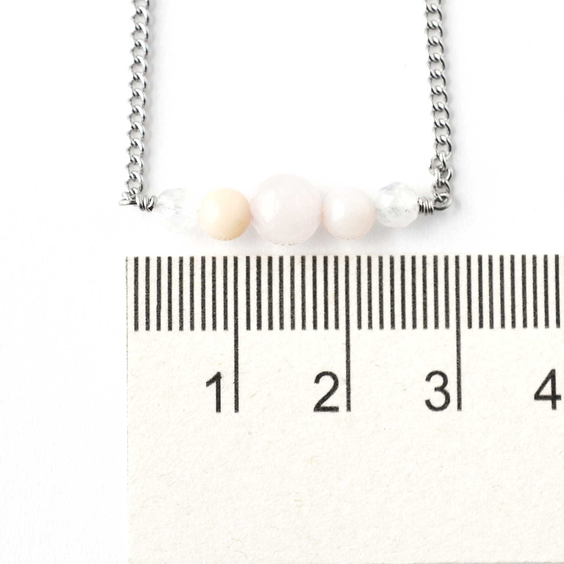 Dainty pale pink gemstone bar necklace next to ruler