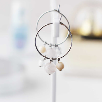 Pale pink gemstone hoop earrings hanging against soft focus background