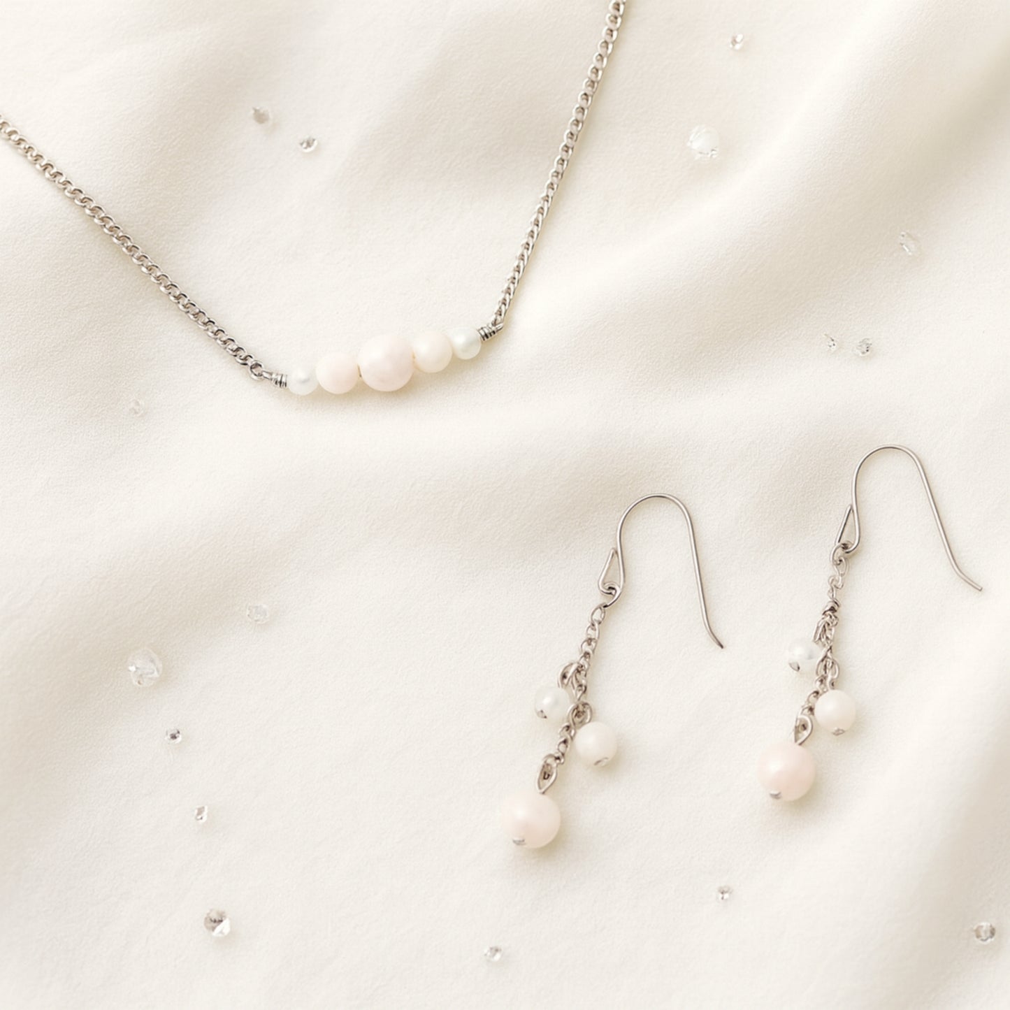 Pale pink gemstone necklace and earrings on a light background