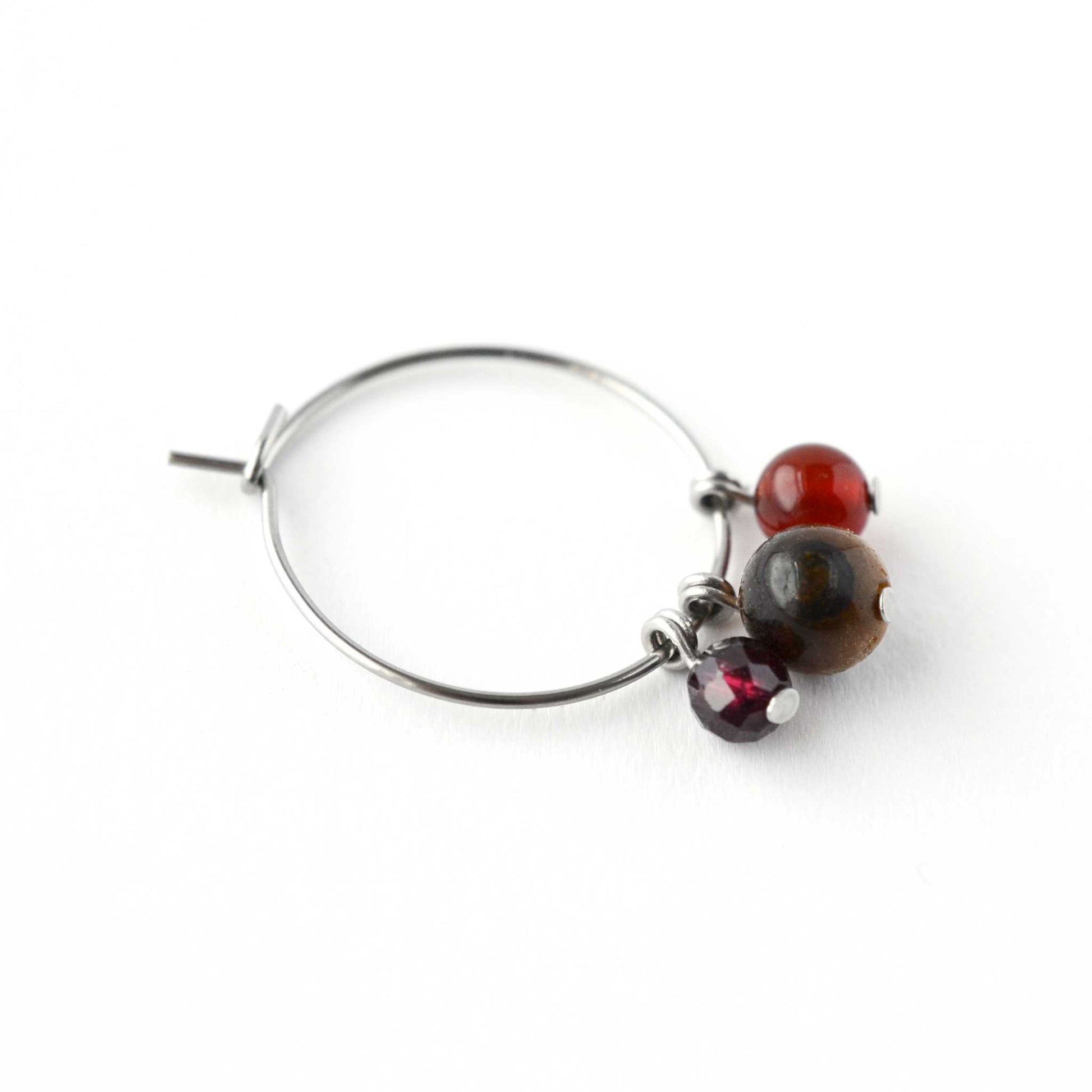 Close up of Garnet, Tigers Eye & Carnelian gemstone beads hanging from hoop earring