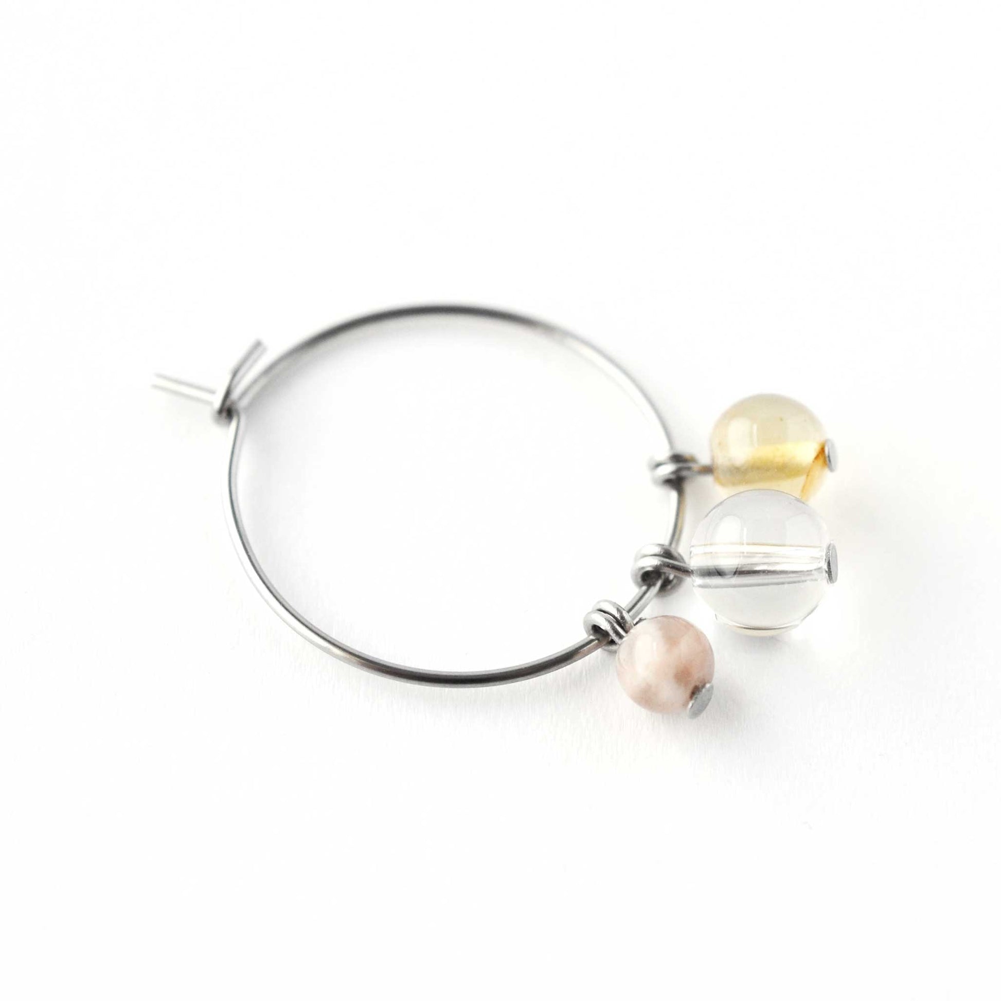 Close up of Sunstone, Rock Crystal & Citrine round gemstone beads hanging from hoop earring