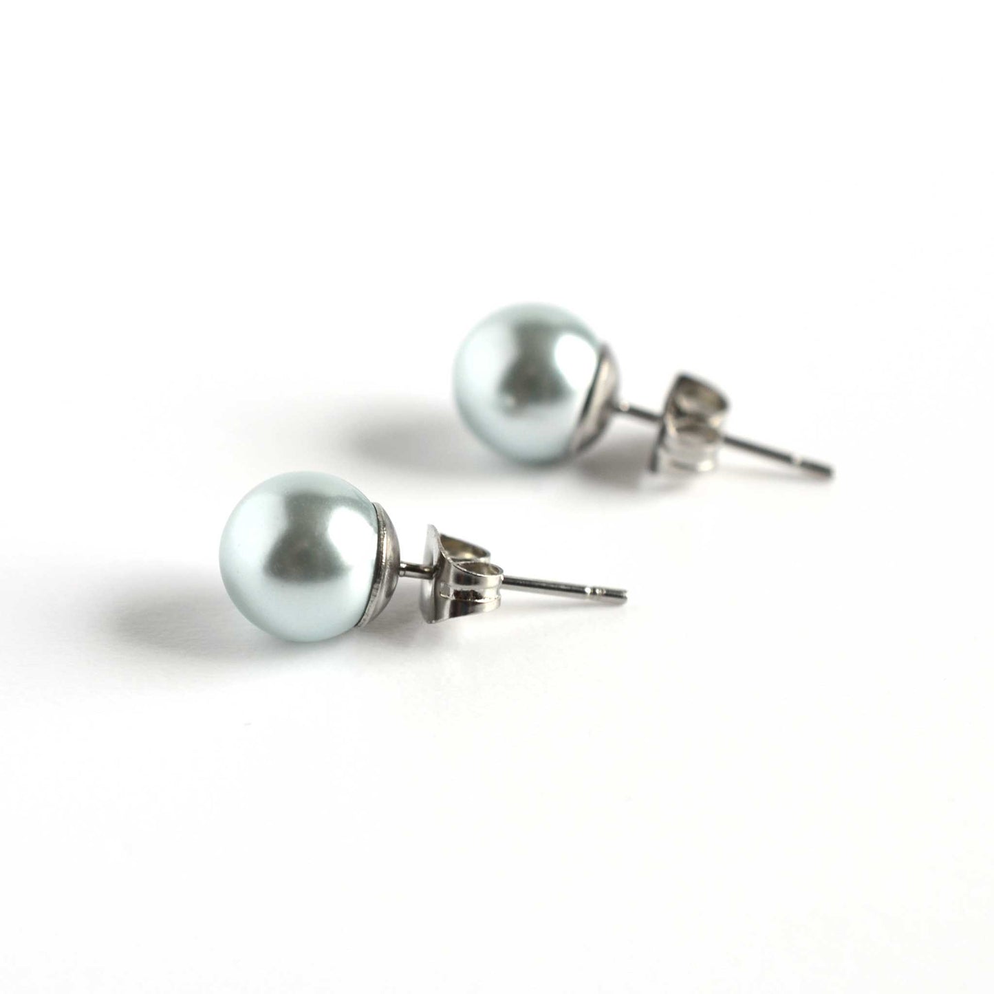 Side view of 8mm light blue faux pearl stud earrings on white background