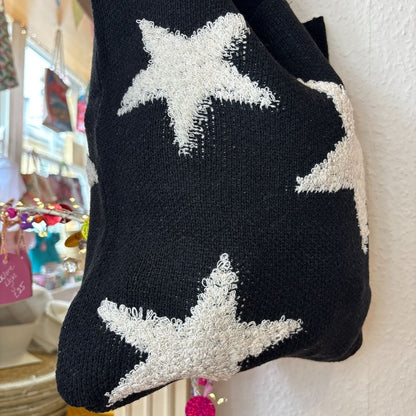 Black bag with white star patterns hanging on a wall.