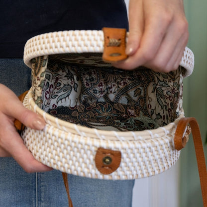 Person holding a woven handbag with a patterned interior