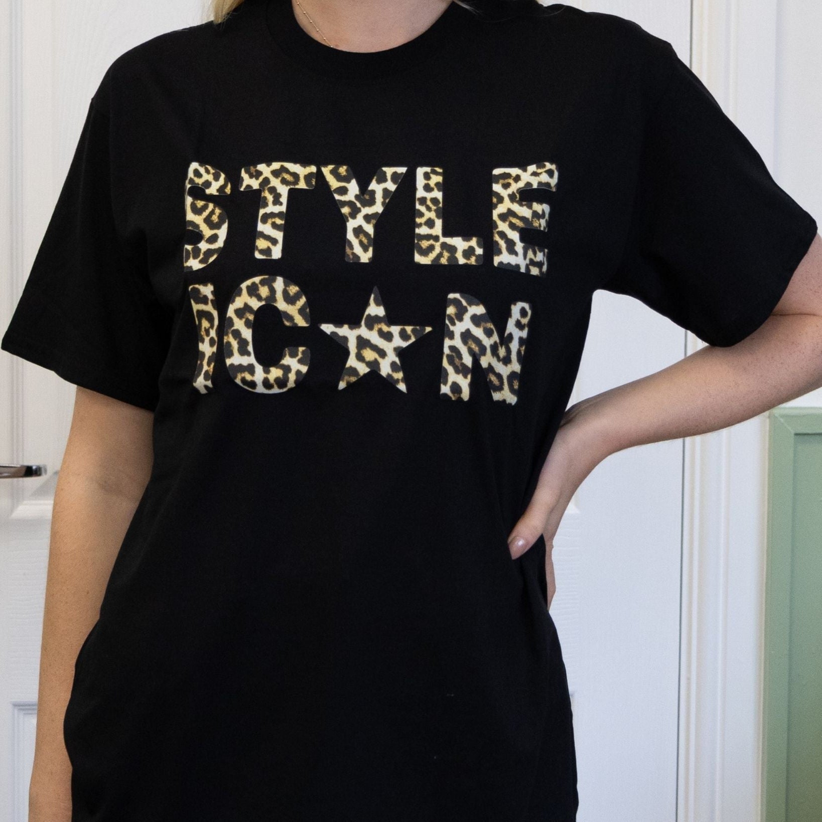 Person wearing a black t-shirt with 'STYLE ICON' in leopard print text.