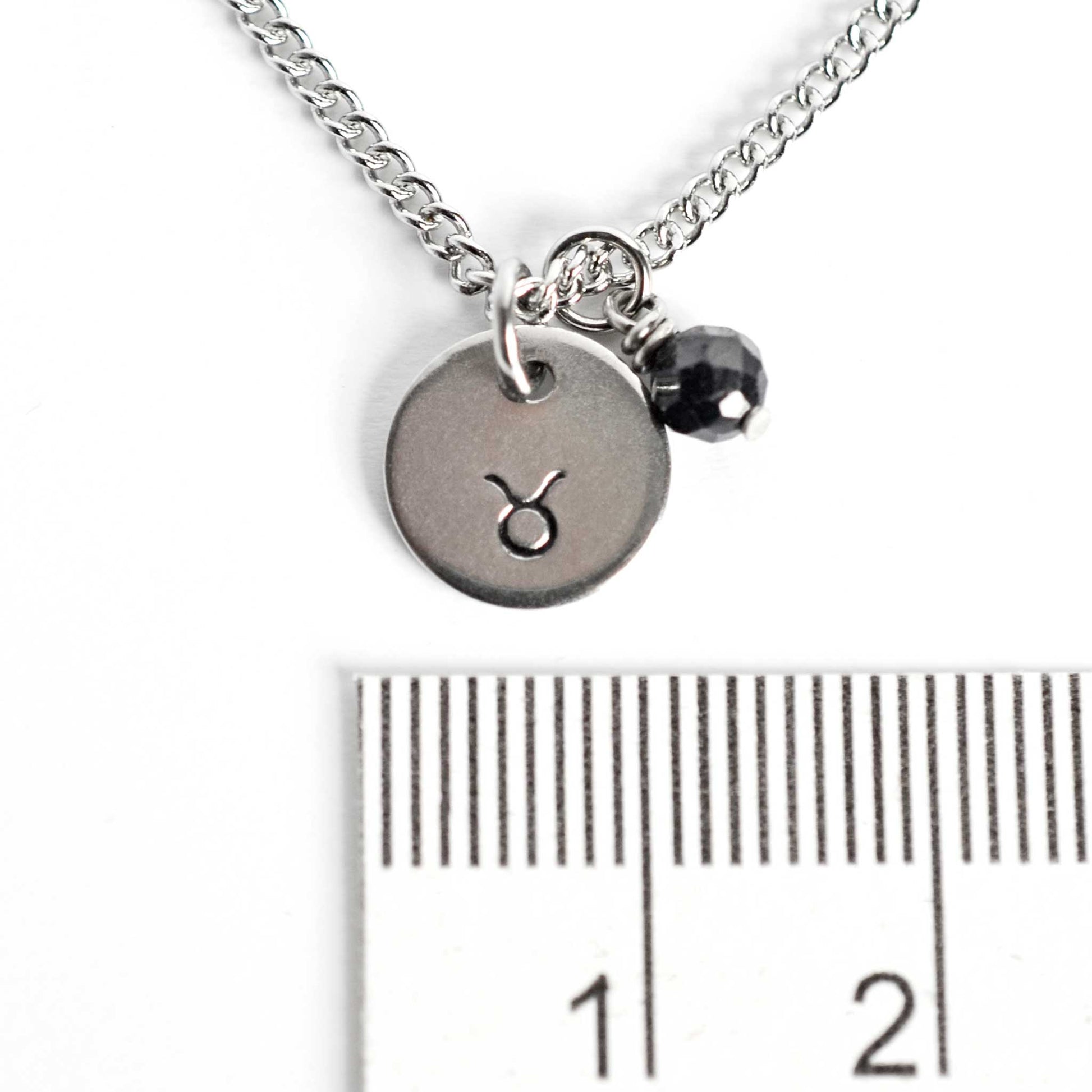 1cm diameter disc pendant with hand stamped Taurus zodiac sign and 4mm Sapphire gemstone charm