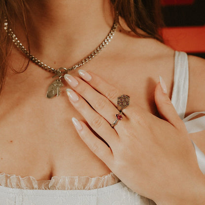 Close-up of a person wearing a necklace and ring with a blurred background
