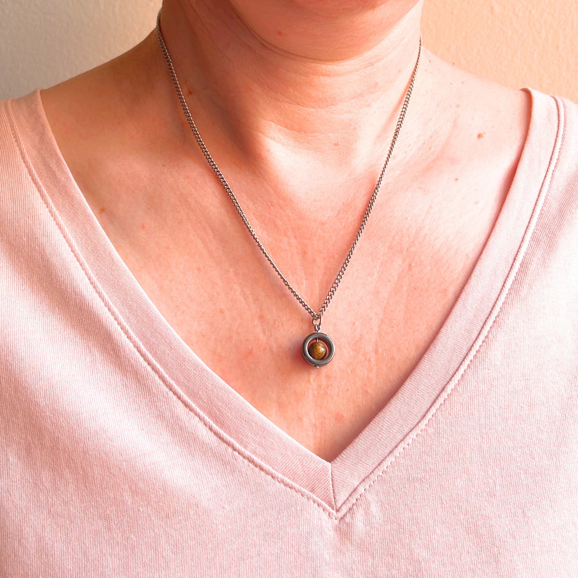 Woman wearing pink v neck top and Tiger's Eye gemstone necklace.