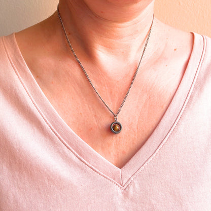 Woman wearing pink v neck top and Tiger's Eye gemstone necklace.