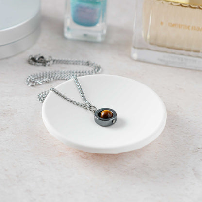 Dainty Tigers Eye gemstone necklace laying on a white trinket dish.