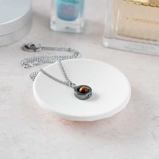 Dainty Tigers Eye gemstone necklace laying on a white trinket dish.