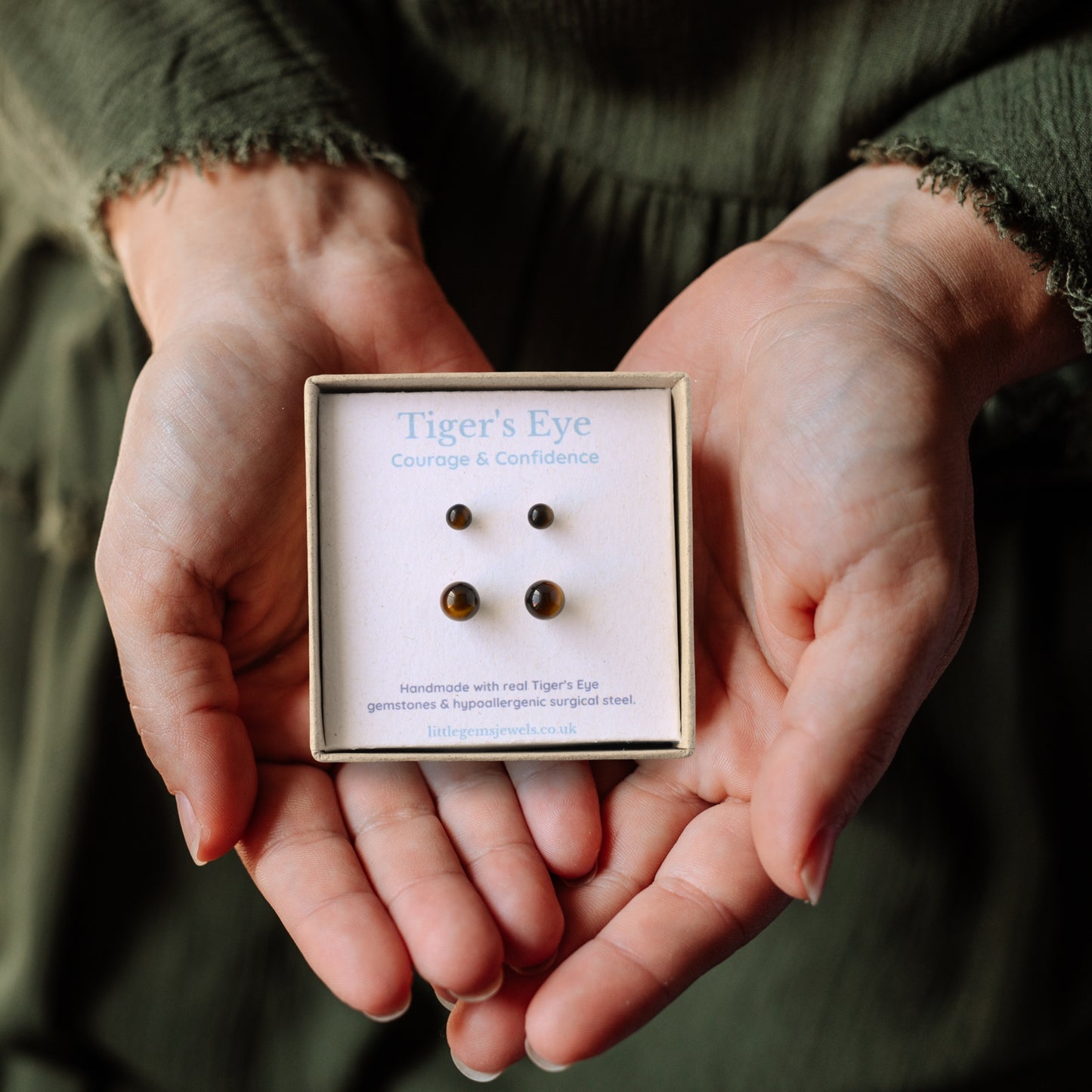 Set of two Tiger's Eye stud earrings in a gift box being held in hands.
