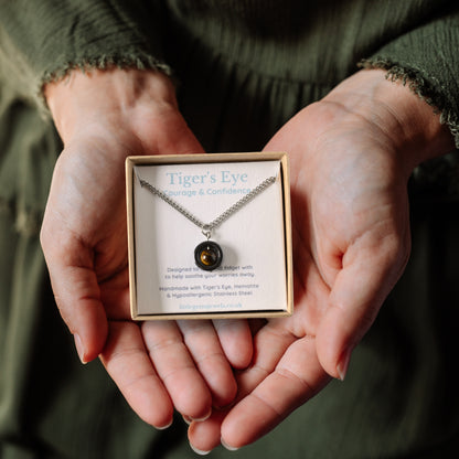 Tigers Eye gemstone spinner necklace in a gift box being held in hands.
