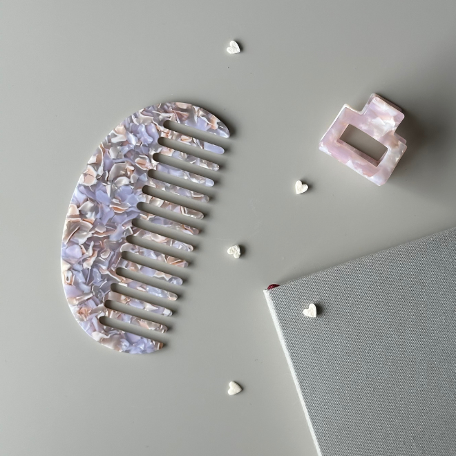 Decorative hair comb and clip on a gray surface with small decorative items.