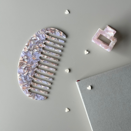Decorative hair comb and clip on a gray surface with small decorative items.