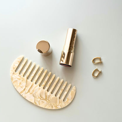 Cream comb and lipstick on a light gray background