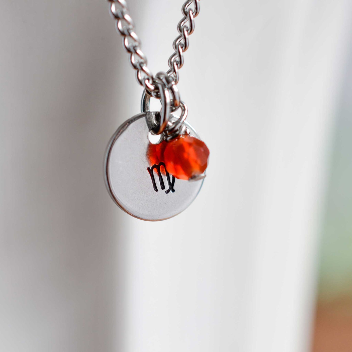 Close up of Virgo zodiac sign necklace with Carnelian gemstone charm on stainless steel chain