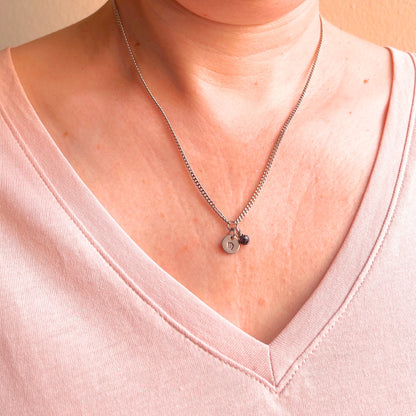 Woman wearing a pink v neck top and dainty Virgo zodiac sign necklace.