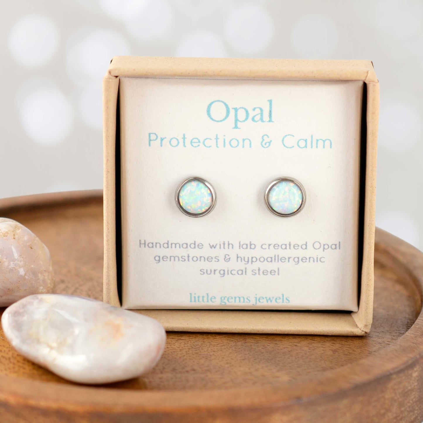 Opal earrings in a 'Protection & Calm' box with stones on a wooden surface