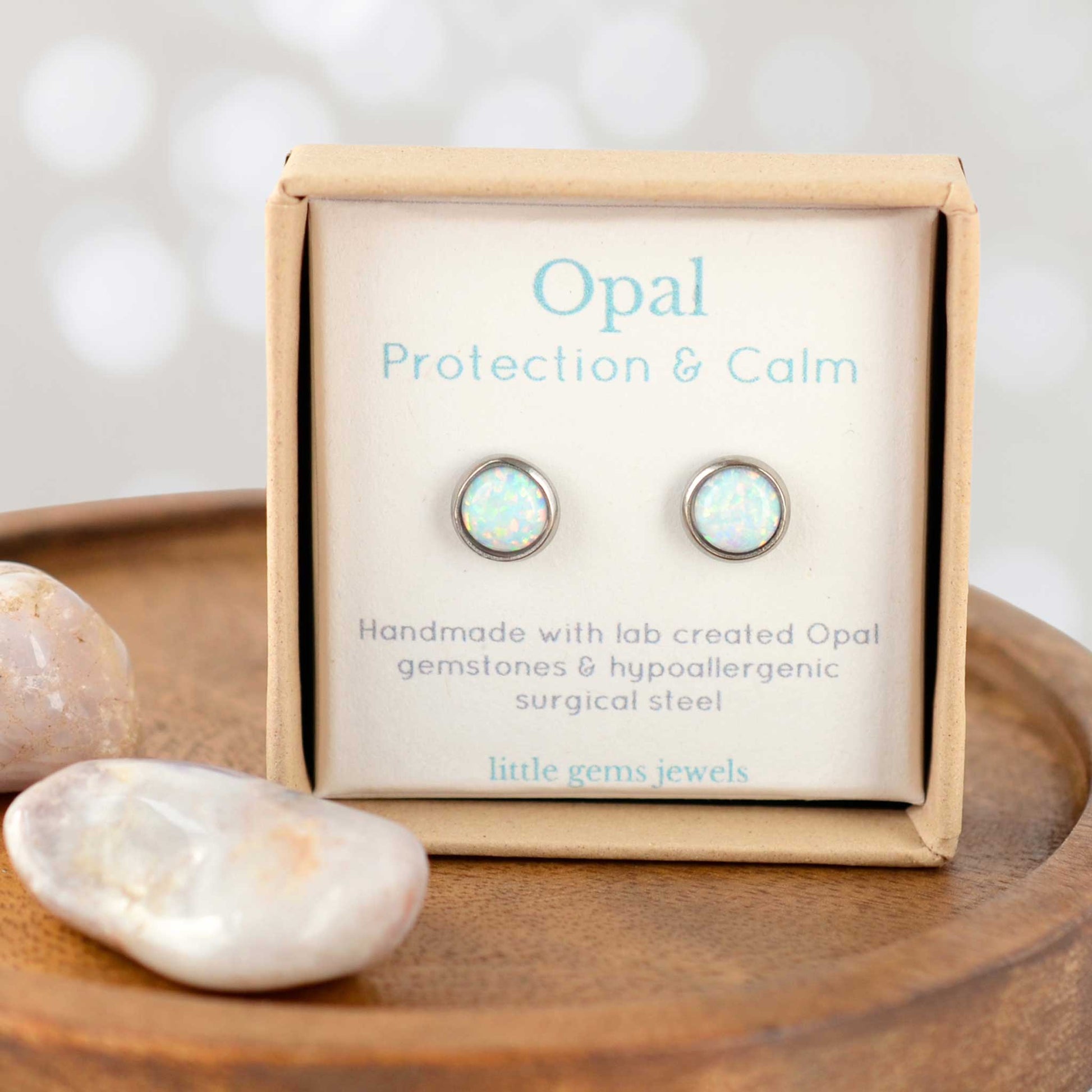 Opal earrings in a 'Protection & Calm' box with stones on a wooden surface