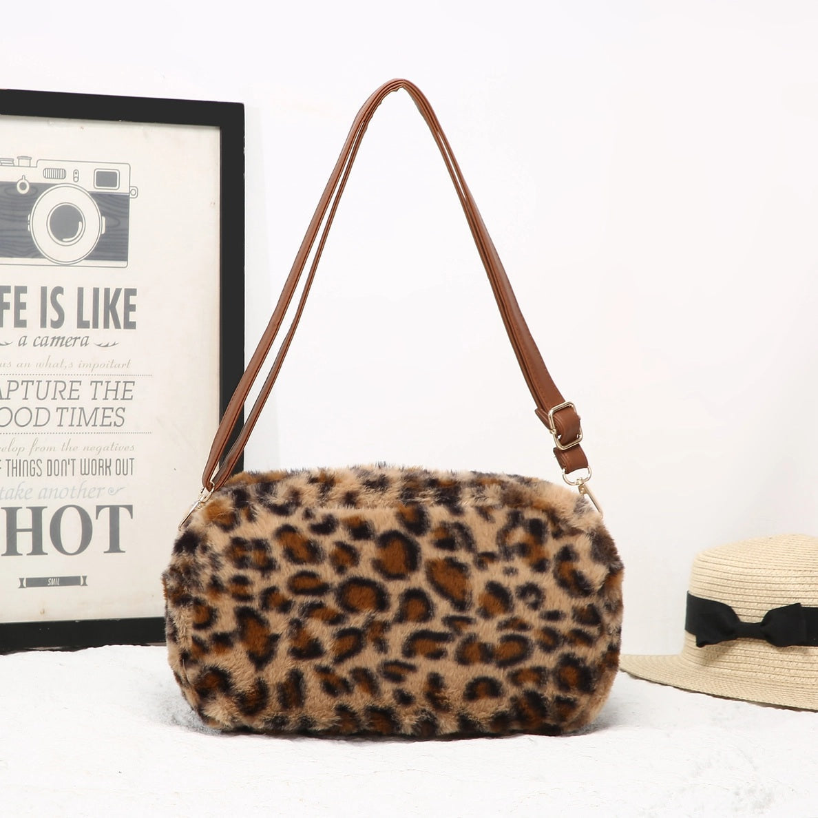 Leopard print handbag with brown strap on a white background