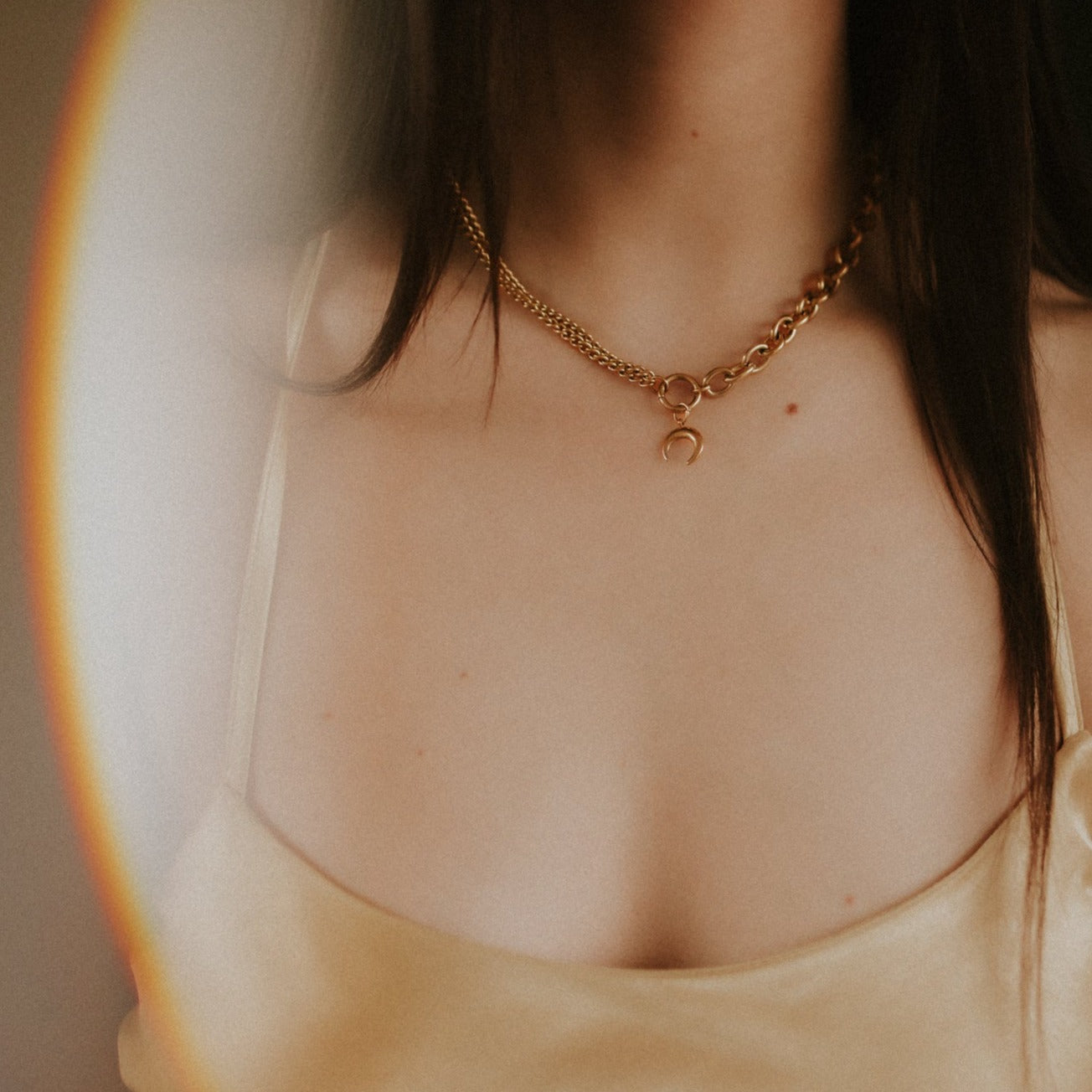 Close-up of a person wearing a gold chain necklace with a blurred background