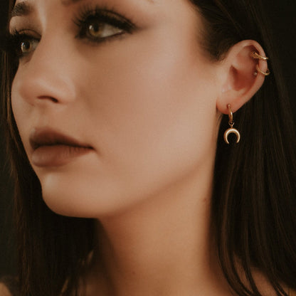 Close-up of a woman wearing gold earrings with a dark background