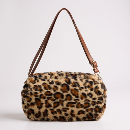 Leopard print handbag with brown leather strap on a light gray background