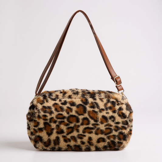 Leopard print handbag with brown leather strap on a light gray background
