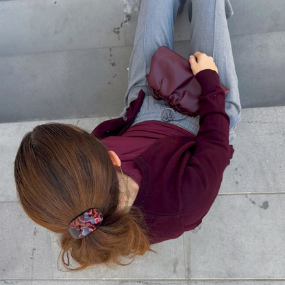 Person sitting on a concrete step with a maroon bag and gray pants