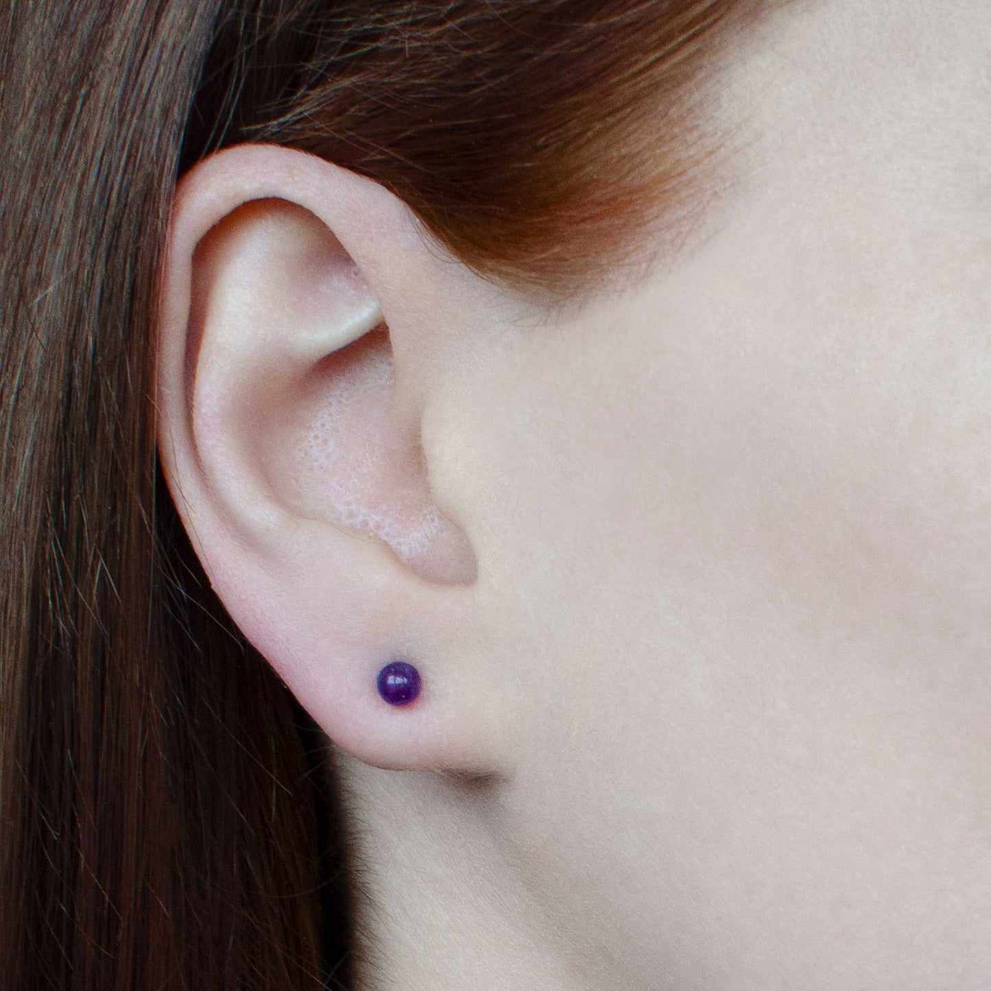 Woman wearing small Amethyst stud earring in earlobe