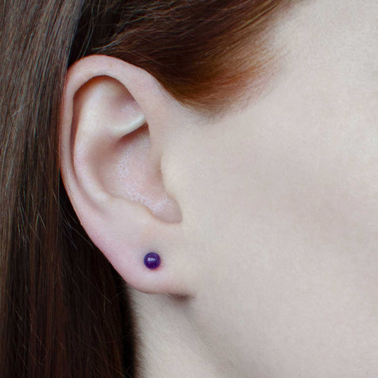 Woman wearing small Amethyst stud earring in earlobe